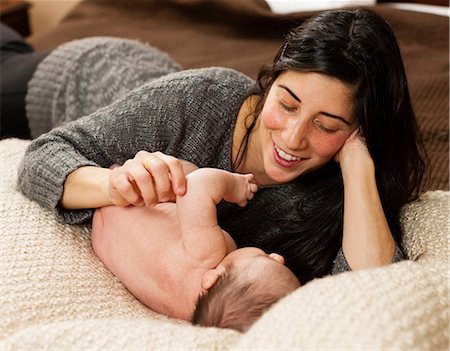 Mother cradling newborn infant on bed Stock Photo - Premium Royalty-Free, Code: 614-06720131