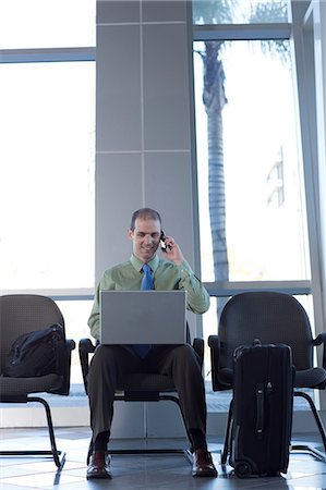 Businessman on cell phone using laptop Stock Photo - Premium Royalty-Free, Code: 614-06813226