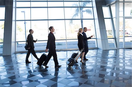Businesspeople walking through airport with suitcases Stock Photo - Premium Royalty-Free, Code: 614-06813221