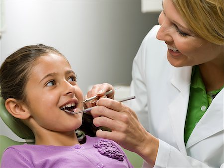 scrutiny - Dentist looking at young girl's teeth Stock Photo - Premium Royalty-Free, Code: 614-06895735