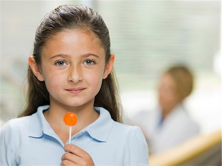 polo shirt - Young girl holding lollipop at the dentist's office, portrait Stock Photo - Premium Royalty-Free, Code: 614-06895754
