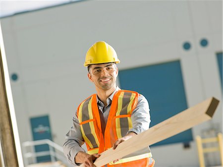 Mid adult construction worker holding wood Stock Photo - Premium Royalty-Free, Code: 614-06895841