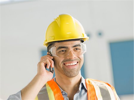 Mid adult construction worker using mobile phone, smiling Stock Photo - Premium Royalty-Free, Code: 614-06895842