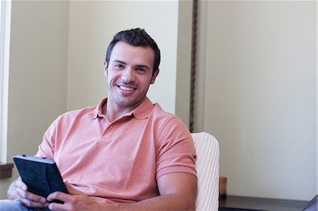 polo shirt - Young man using electronic book, portrait Stock Photo - Premium Royalty-Free, Code: 614-06895927