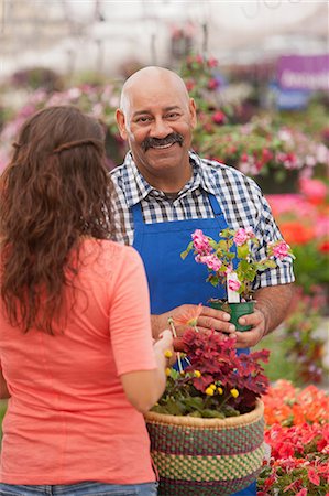 portrait man shirt shop - Mature man serving young woman in garden centre, portrait Stock Photo - Premium Royalty-Free, Code: 614-06896170