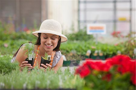 simsearch:649-07280682,k - Young woman looking at plants in garden centre, smiling Photographie de stock - Premium Libres de Droits, Code: 614-06896187