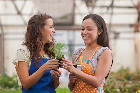 simsearch:614-07806416,k - Young women holding plant in garden centre, smiling Photographie de stock - Premium Libres de Droits, Code: 614-06896189