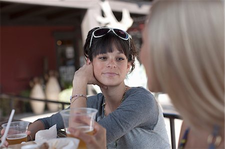 Girlfriends having drinks in outdoor cafe, smiling Stock Photo - Premium Royalty-Free, Code: 614-06896237
