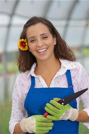 Young woman holding pruning shears in garden centre, portrait Stock Photo - Premium Royalty-Free, Code: 614-06896233