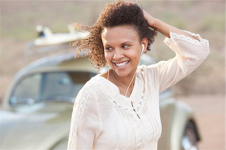 simsearch:614-06896253,k - Young woman wearing earphones in desert on road trip, smiling Stock Photo - Premium Royalty-Free, Code: 614-06896244