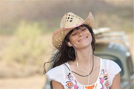 simsearch:614-06896253,k - Young woman in cowboy hat wearing earphones, smiling Stock Photo - Premium Royalty-Free, Code: 614-06896247