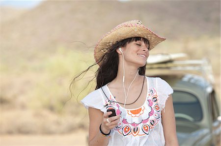 simsearch:614-06896253,k - Young woman in cowboy hat wearing earphones, smiling Stock Photo - Premium Royalty-Free, Code: 614-06896248