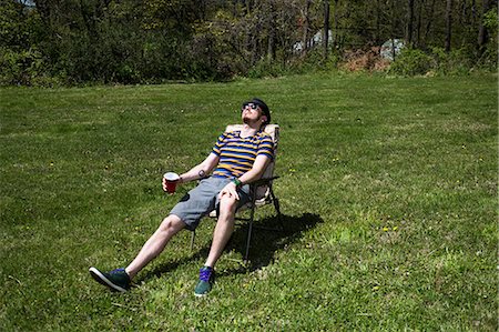 Man sitting on chair sunbathing Stock Photo - Premium Royalty-Free, Code: 614-06896607