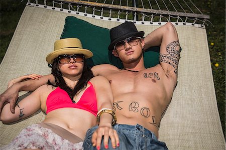 Couple wearing hats and sunglasses lying in hammock Stock Photo - Premium Royalty-Free, Code: 614-06896614