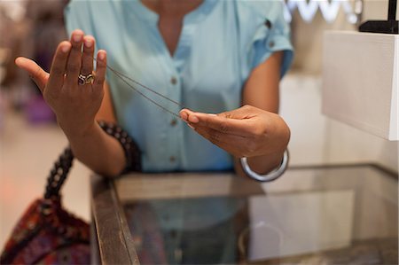 people vintage - Young woman holding necklace in vintage shop Stock Photo - Premium Royalty-Free, Code: 614-06896753