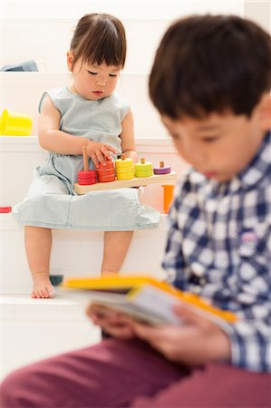 Brother and sister playing with toys on stairs Stock Photo - Premium Royalty-Free, Code: 614-06896930