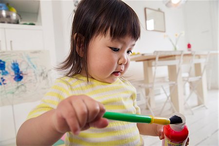 Female toddler holding paintbrush and paint Stock Photo - Premium Royalty-Free, Code: 614-06896956