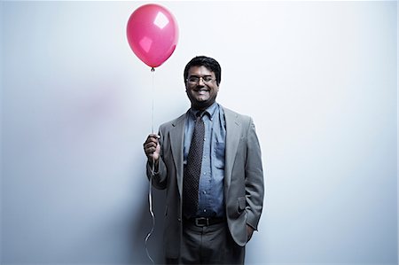 funny images of indian people - Studio portrait of businessman holding red balloon Stock Photo - Premium Royalty-Free, Code: 614-06897210