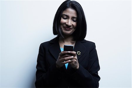 expresión facial - Studio portrait of businesswoman looking at cellphone Foto de stock - Sin royalties Premium, Código: 614-06897229