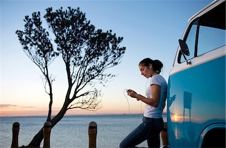 Young woman leaning on camper van at dusk Foto de stock - Sin royalties Premium, Código: 614-06897282