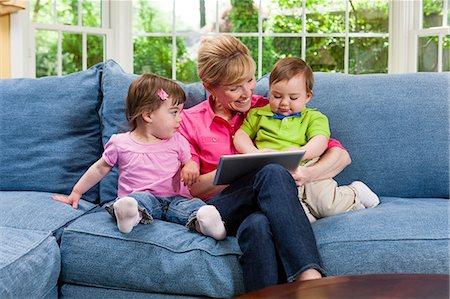 eco friendly home - Grandmother and grandchildren on sofa looking at digital tablet Stock Photo - Premium Royalty-Free, Code: 614-06897442