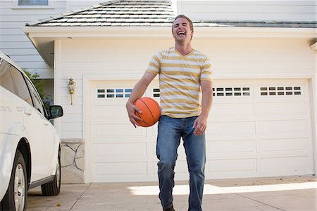 Young man holding basketball laughing, portrait Stock Photo - Premium Royalty-Free, Code: 614-06897589