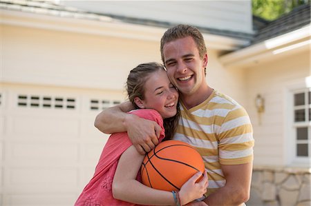 Brother with arm around sister holding basketball Stock Photo - Premium Royalty-Free, Code: 614-06897601