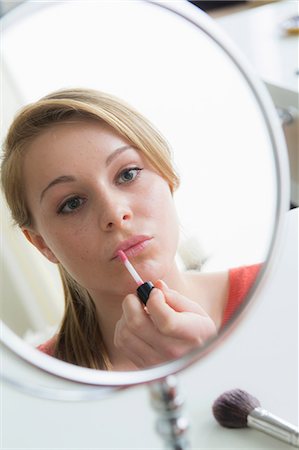 Teenage girl applying lip gloss Stock Photo - Premium Royalty-Free, Code: 614-06897812