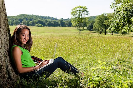 Young woman using laptop sitting by tree Stock Photo - Premium Royalty-Free, Code: 614-06898104