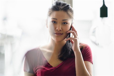 Woman on mobile phone looking at camera Stock Photo - Premium Royalty-Free, Code: 614-06898471
