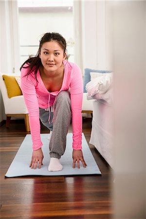 Woman in yoga pose looking at camera Stock Photo - Premium Royalty-Free, Code: 614-06898485