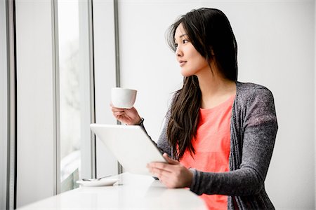 person holding cup of coffee - Woman with digital tablet during break looking out window Stock Photo - Premium Royalty-Free, Code: 614-06898517