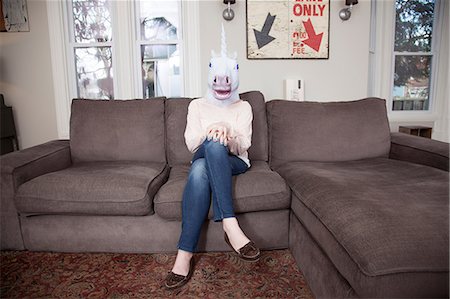 esconderse - Girl sitting on sofa wearing unicorn head mask Foto de stock - Sin royalties Premium, Código: 614-06974335