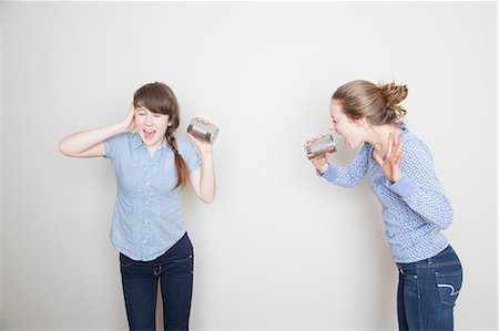 screaming (human yelling) - Two girls with tin cans, one shouting and one covering her ear Stock Photo - Premium Royalty-Free, Code: 614-06974354