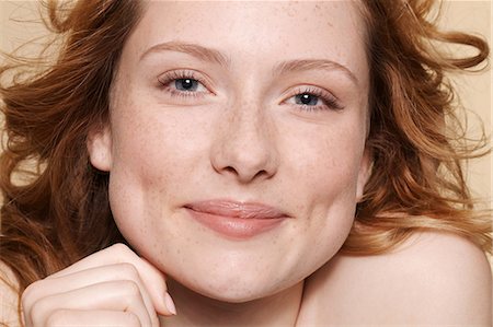 freshly - Studio shot of young woman with curly red hair, hand on chin Stock Photo - Premium Royalty-Free, Code: 614-06974524
