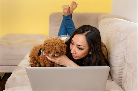 Mid adult female lying on sofa with dog looking at laptop Stock Photo - Premium Royalty-Free, Code: 614-06974762