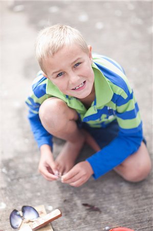Portrait of young boy sitting on pier with seashell Stock Photo - Premium Royalty-Free, Code: 614-06973751
