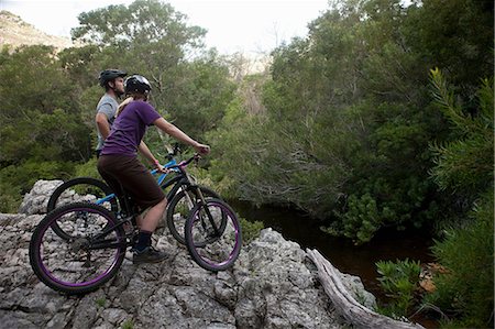 Young couple on mountain bikes on edge of rock Stock Photo - Premium Royalty-Free, Code: 614-06973796