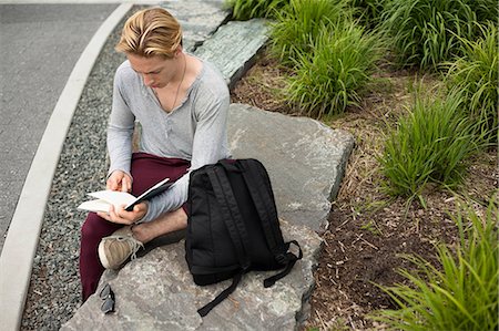 person tshirt rucksack - Young man studying text book in park Stock Photo - Premium Royalty-Free, Code: 614-07031096