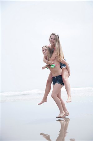 Young woman on piggyback on beach Stock Photo - Premium Royalty-Free, Code: 614-07031118