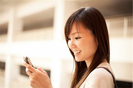 Mid adult woman looking at mobile phone, smiling Stock Photo - Premium Royalty-Free, Code: 614-07031439