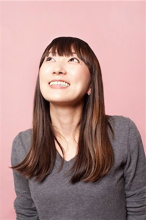 Mid adult woman smiling and looking up against pink background Foto de stock - Sin royalties Premium, Código: 614-07031443