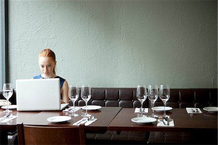 Young woman using laptop in restaurant Stock Photo - Premium Royalty-Free, Code: 614-07031527