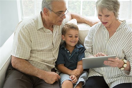 senior technology - Grandparents showing boy digital tablet on sofa Stock Photo - Premium Royalty-Free, Code: 614-07031719