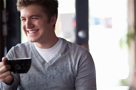 smiling portrait looking away - Portrait of young man in cafe holding cup Stock Photo - Premium Royalty-Free, Code: 614-07031976