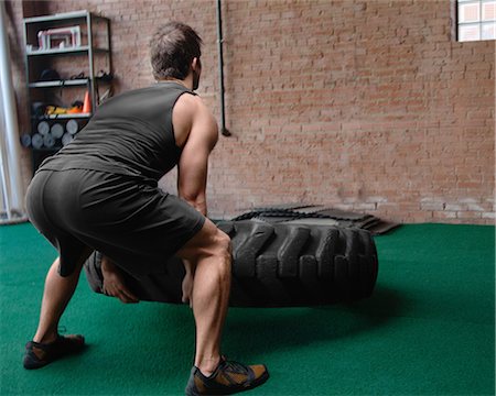 Male bodybuilder lifting tyre Stock Photo - Premium Royalty-Free, Code: 614-07032203