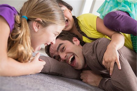daughter with dad in home - Girls tickling father Stock Photo - Premium Royalty-Free, Code: 614-07146328