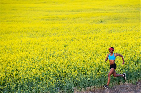 Young woman running next to oil seed rape field Stock Photo - Premium Royalty-Free, Code: 614-07146379