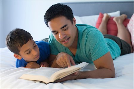 Father and son reading on bed Stock Photo - Premium Royalty-Free, Code: 614-07146569