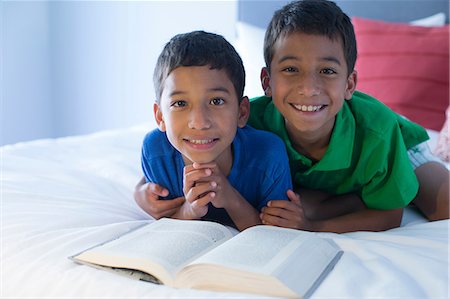 Brothers looking up from book on bed Stock Photo - Premium Royalty-Free, Code: 614-07146572